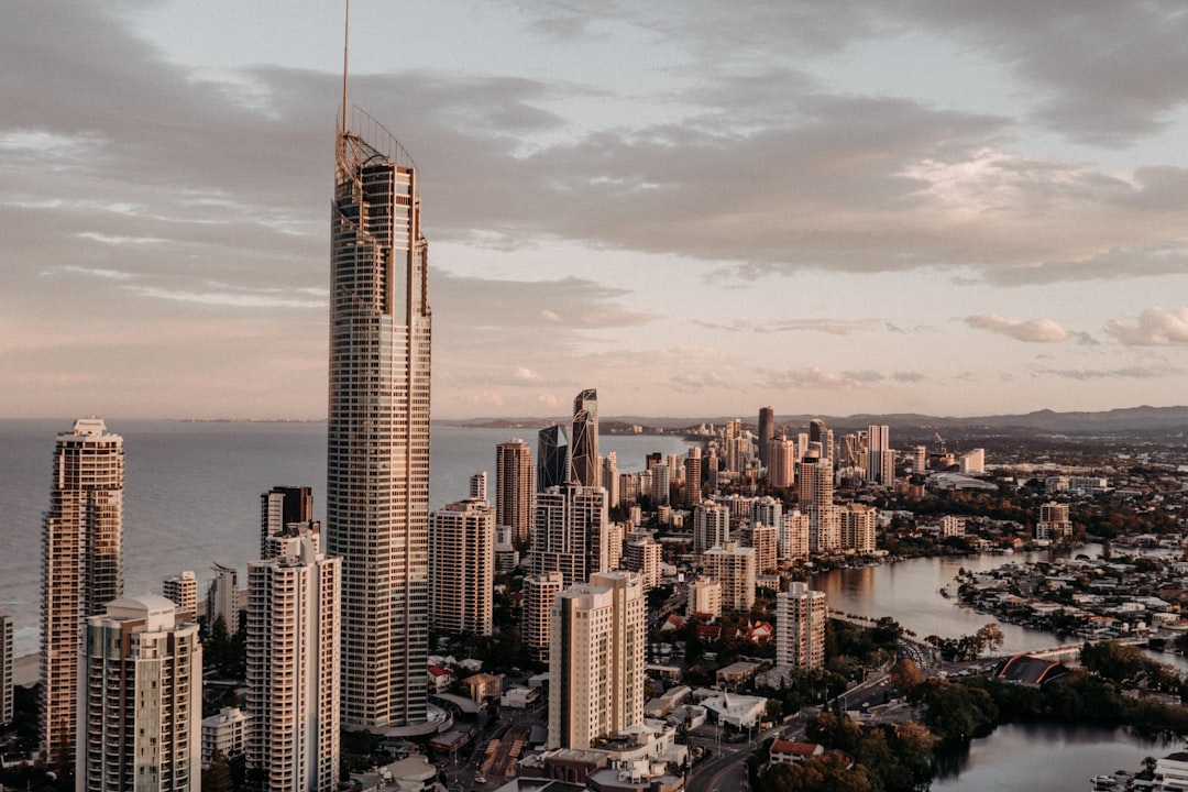 A drone photo of the Gold Coast skyline with skyscrapers, with one tall building in front of it and an ocean view behind it, golden hour lighting, cinematic, editorial photography, professional color grading, shot in the style of Hasselblad X2D. –ar 128:85