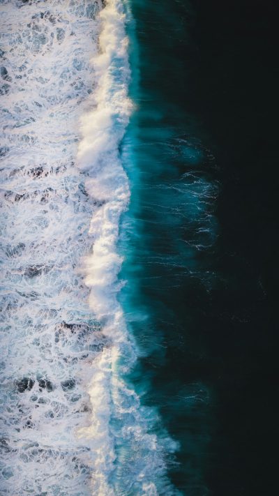 Photo of an ocean, taken from above, drone shot, white and blue waves, dark background, hyper realistic photography --ar 9:16