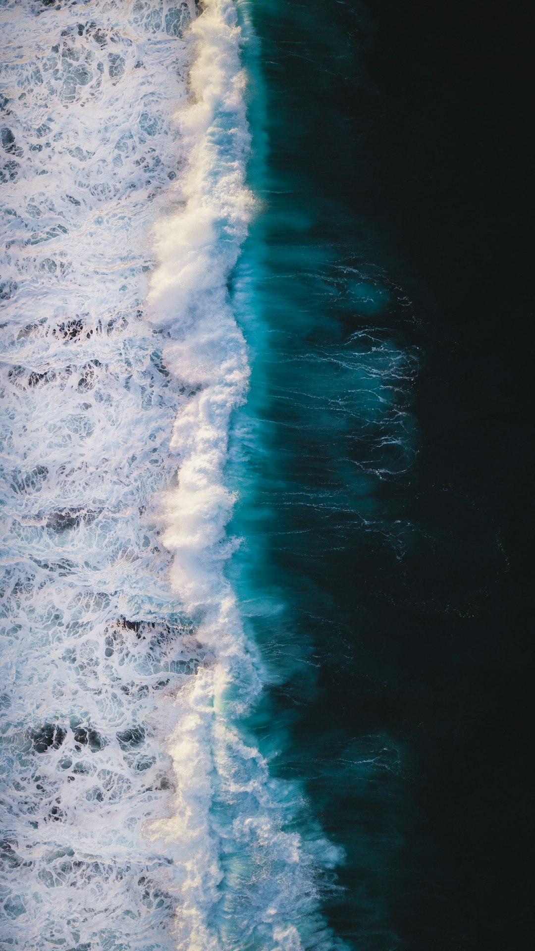 Photo of an ocean, taken from above, drone shot, white and blue waves, dark background, hyper realistic photography –ar 9:16