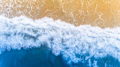Aerial view of sea waves with foam on the beach background, from a top down perspective, in a photo realistic, high resolution photographic style, with high details, high quality, and high sharpness, in the hyperrealistic style, stock photo, taken in the style of Canon EOS C300 Mark III and Zeiss Batis 25mm f/8, with a bokeh effect, colorful, on a sunny day during the golden hour. --ar 16:9