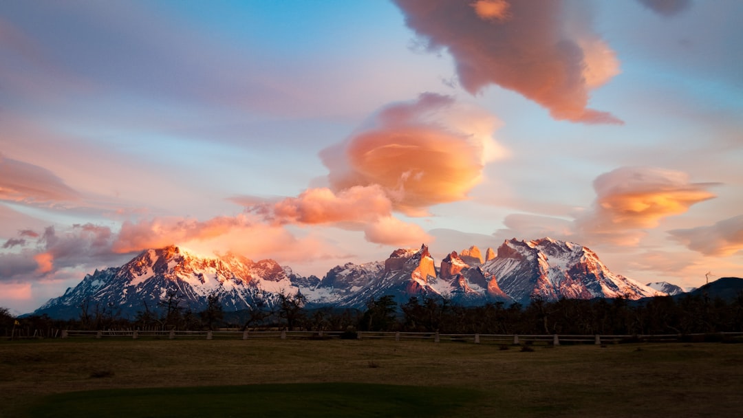 photograph of the peaks in patagonia with lanters shaped clouds at sunset with an golf course foreground –ar 16:9