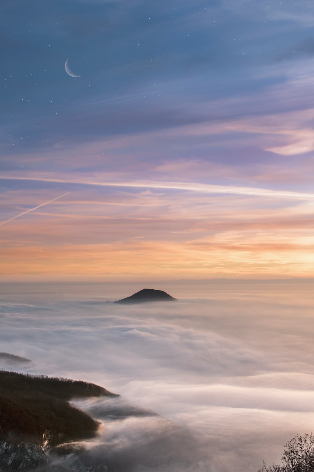 A distant view of the moon rising above an island in thick fog, seen from high up on top of Mount H masculinity, a sky with stars and the crescent moon, a serene dawn light casting long shadows over the mistcovered sea, a color palette of soft pastel hues blending into each other, creating a dreamlike atmosphere, captured using Nikon D850 camera with Nikon AFS NIKKOR 2470mm f/2.8E ED VR lens –ar 85:128