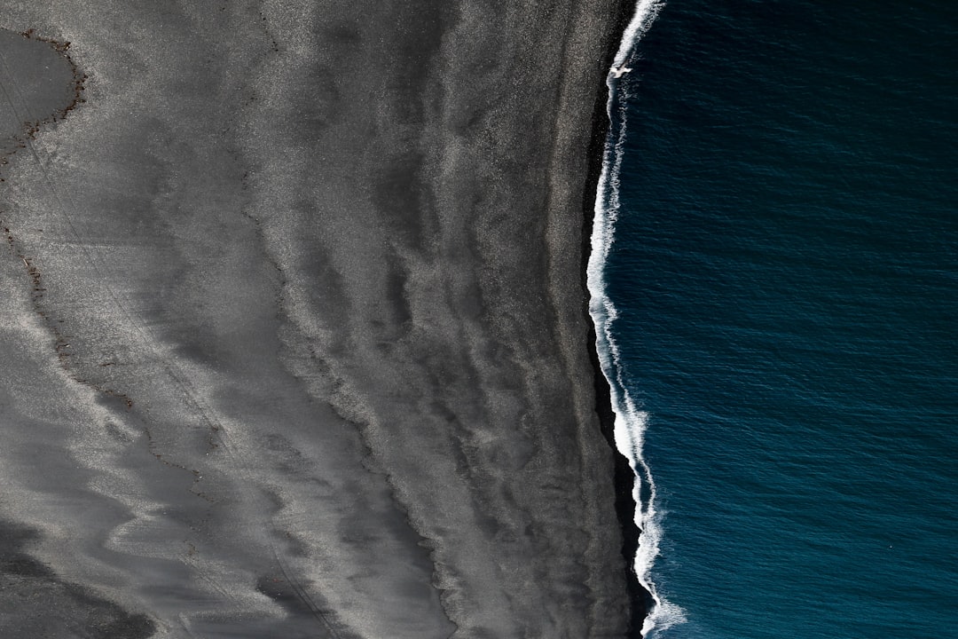 aerial view of black sand beach, ocean waves, drone photography, minimalist, dark blue and gray tones –ar 128:85