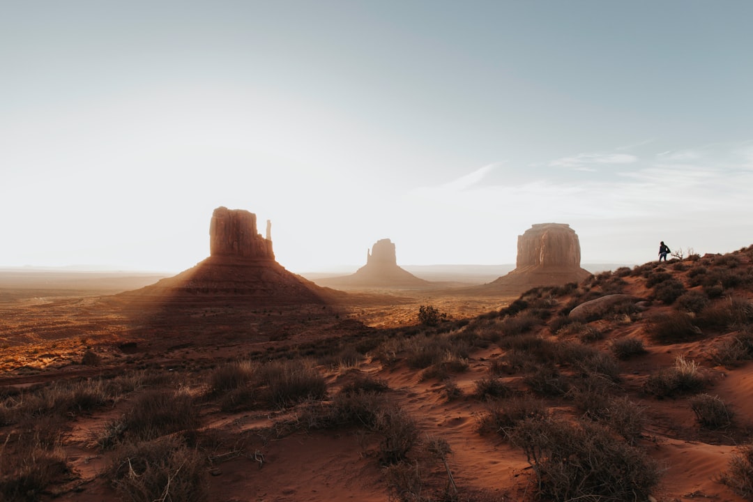 A photo of the desert landscape with two rock formations in Monument Valley, soft light, minimal, vastness, golden hour, a lone biker riding down the horizon in the style of unsplash photography. –ar 128:85