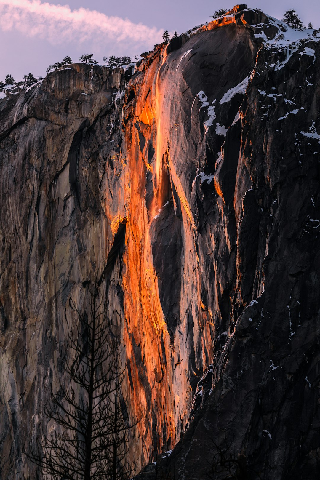 A photograph of the rock face in Yosemite National Park, orange light shines on it like an amber waterfall. Sunrise lighting creates a perfect composition with golden hour lighting following the rule of thirds for professional, award winning photography in the style of a professional photographer. –ar 85:128