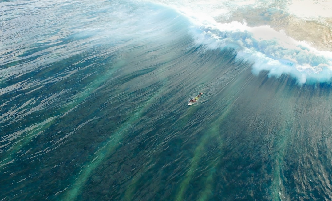 aerial view of surfer riding wave in the ocean, wide shot, drone photography, photorealistic landscapes, national geographic photography, stockphoto, stockphoto, professional color grading, depthoffield –ar 128:77