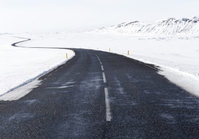 Winding asphalt road in the snow-covered Icelandic landscape, wide-angle view, white sky, empty highway with clear weather, winter travel concept, travel photography, stock photo. --ar 128:89