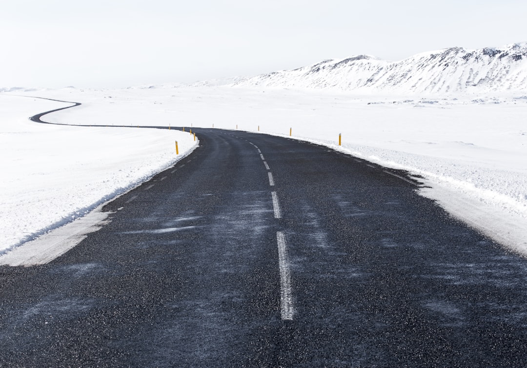 Winding asphalt road in the snow-covered Icelandic landscape, wide-angle view, white sky, empty highway with clear weather, winter travel concept, travel photography, stock photo. –ar 128:89