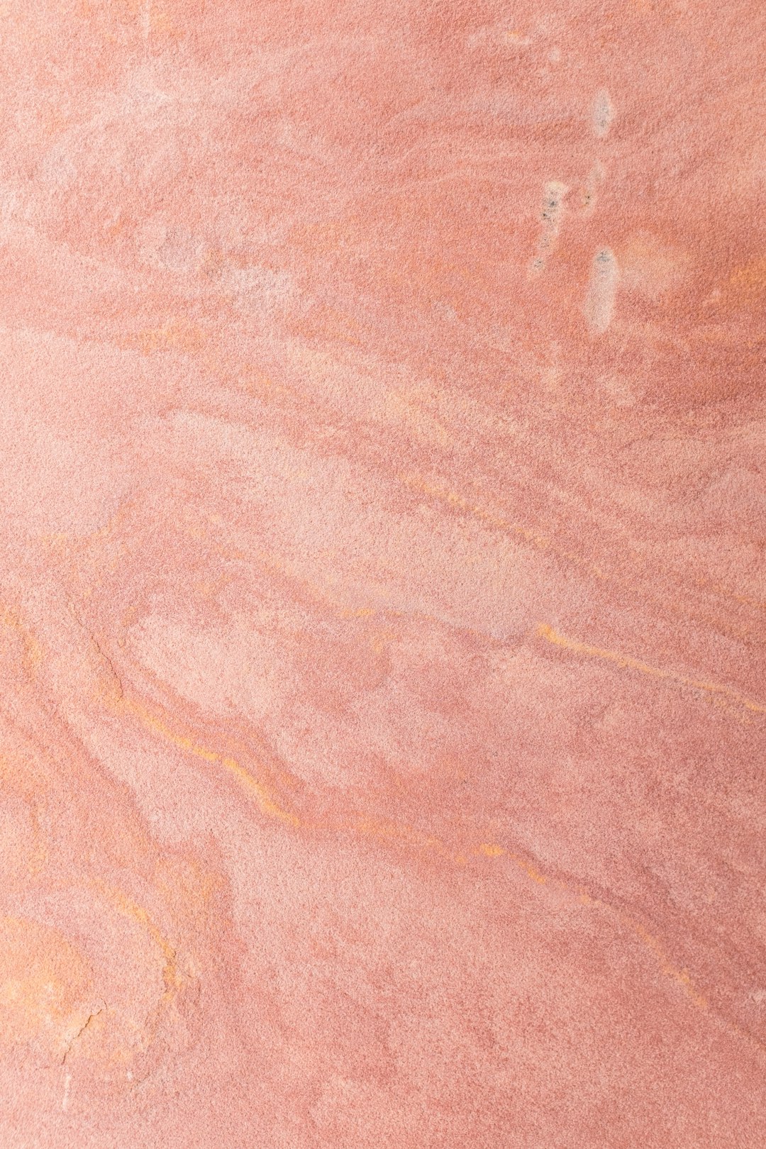 A closeup of the surface texture of pink sandstone, showcasing its unique patterns and colors. The background is plain with no additional elements to highlight the natural beauty of the stone. This photograph was taken by professional photographers using advanced equipment for highly detailed and sharp images. –ar 85:128