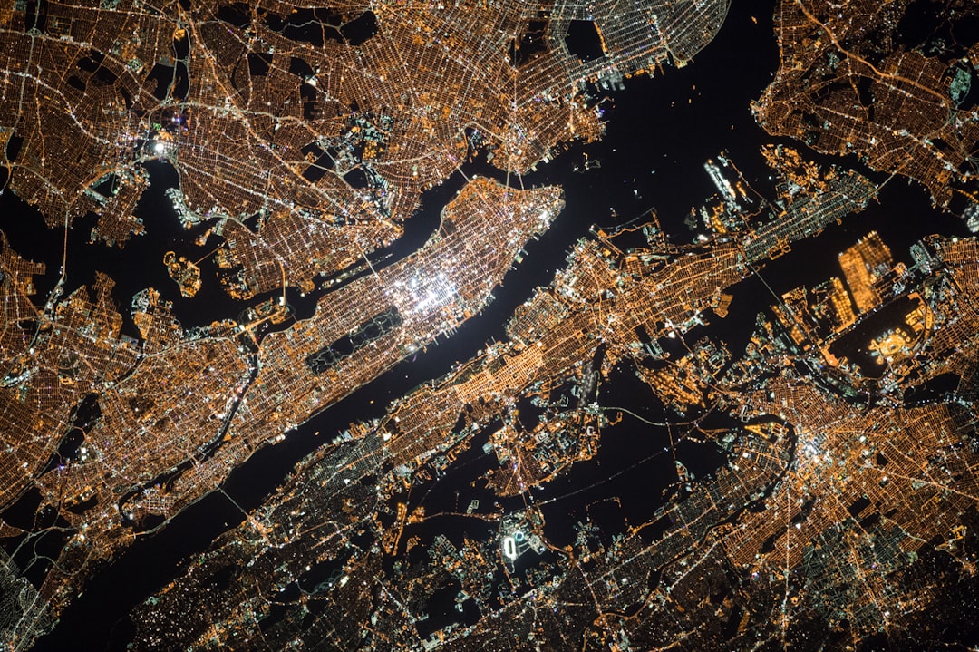 Night view of New York City from the International Space Station, showcasing its city lights and architectural details against black sky, capturing the urban landscape in high resolution, Photography, using a long exposure to capture the vibrant glow of streetlights and buildings, –ar 128:85