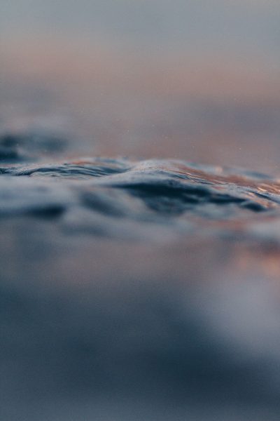 Closeup of the water's surface, gentle waves, and soft pastel colors of dusk, creating an atmosphere of calmness and serenity. Photography, captured with Canon EOS R5 using a macro lens for detailed focus on the water's texture, in the style of no artist. --ar 85:128