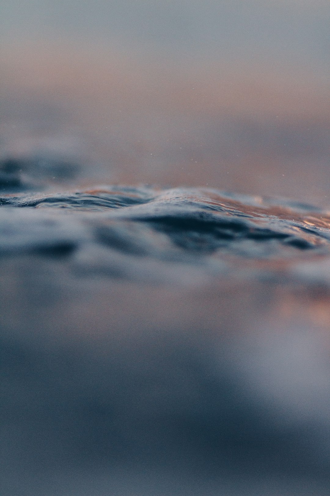 Closeup of the water’s surface, gentle waves, and soft pastel colors of dusk, creating an atmosphere of calmness and serenity. Photography, captured with Canon EOS R5 using a macro lens for detailed focus on the water’s texture, in the style of no artist. –ar 85:128