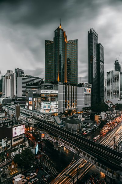 Photography of Bangkok city, tall buildings, busy streets, cloudy sky, Thai shopping mall with yellow light on top building, black and white photography, cinematic style, hyper realistic style. --ar 85:128