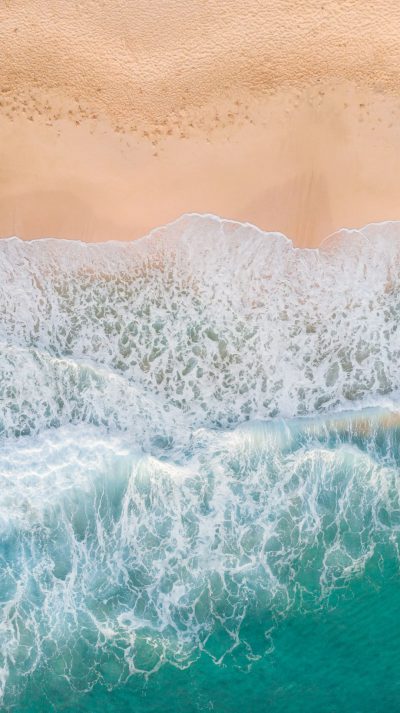 A photo of the top view of waves crashing on an Australian beach, taken from above with a drone. Beautiful sand and turquoise water, soft lighting, natural colours, high resolution, in the style of hyper realistic. --ar 71:128