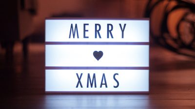 light box with the text "Merry Christmas" on it, white light and black lettering, a heart symbol is between two lines of text, minimalist design, warm lighting, closeup shot, blurred background, high resolution photography --ar 16:9