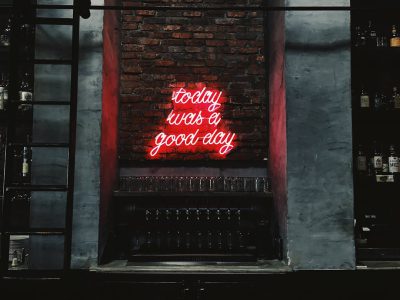 A red neon sign on the wall of an industrial bar that says "esque today was good day --ar 4:3