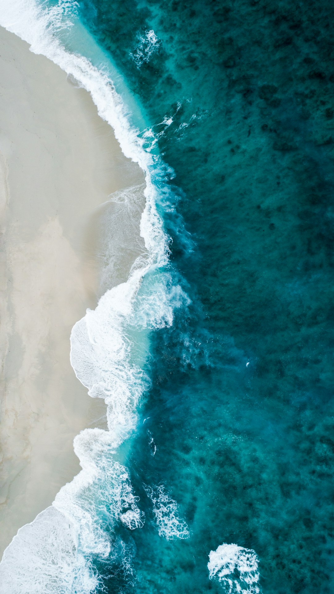 Aerial view of the ocean waves on an Australian beach, with white sand and turquoise water. The scene is captured from above in high resolution, showcasing the beauty of nature’s creation. This photo was taken using a Canon EOS camera and lens, creating a stunning visual experience. High definition photography with sharp focus, natural lighting, and stunning color contrast. The style of the photo is in the style of natural landscape photography. –ar 71:128