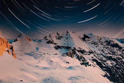 long exposure star trails in the Alps, mountain top with snow and rocks, shot in the style of canon eos r5 --ar 128:85