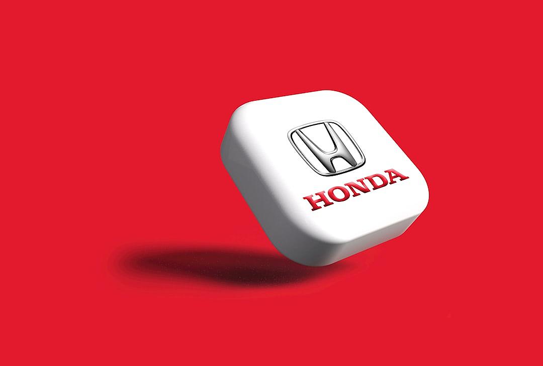 A white, square-shaped button with the Honda logo on it is floating in front of an all red background. The button’s shadow should be rendered as if cast by the falling object and the letters “量递.load” appear at one end of each side of that text below edge of graphic element, the entire design must have a 3D look. This will give depth to your logo. In sharp focus, the photo has been taken from above, the logo stands out against the solid color backdrop. It’s a high resolution, very detailed image in the style of a photograph.