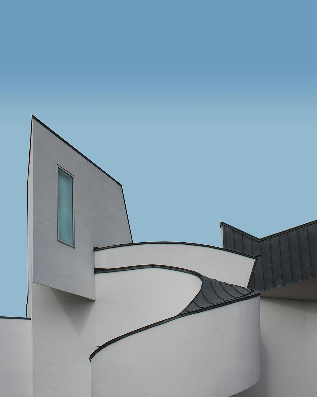 A white museum building raised in the sky, designed with black roof tiles and gray walls, in the style of Vandyk and Neideck, simple lines, curves, minimalist style, light blue background, architectural photography, Leica camera.