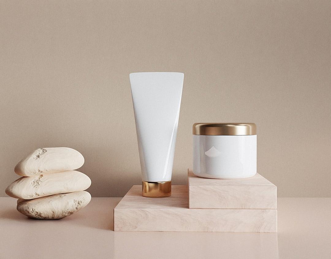 A mockup of two white cosmetic tubes and jars, on top of a beige stone pedestal with a gold rim, with a stack of rocks and a simple background, in soft warm light, beauty photography in the style of minimalism.