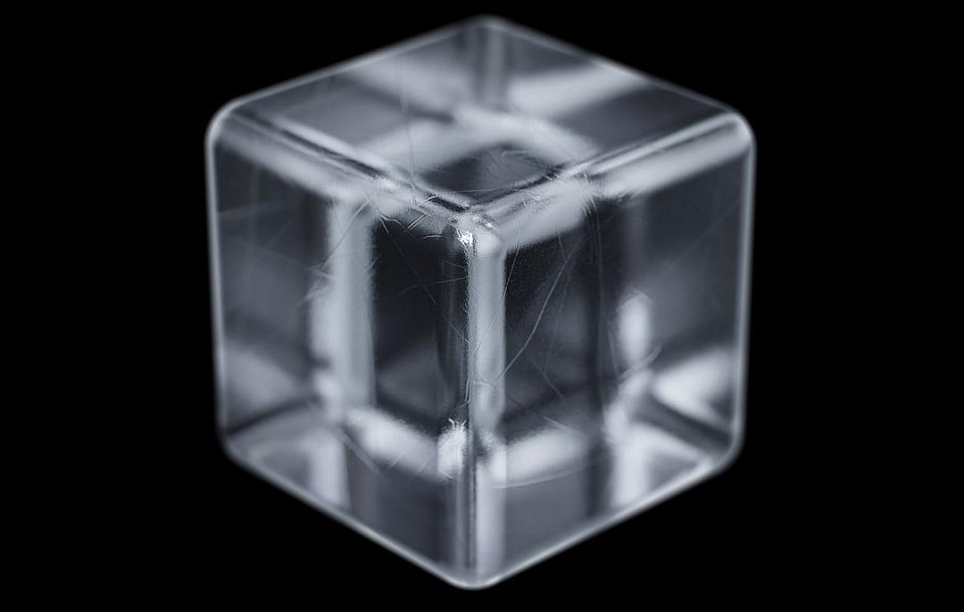 An X-ray of an ice cube, with its internal structure visible in clear detail against the black background. The edges and details can be clearly seen through the glasslike surface of the block.