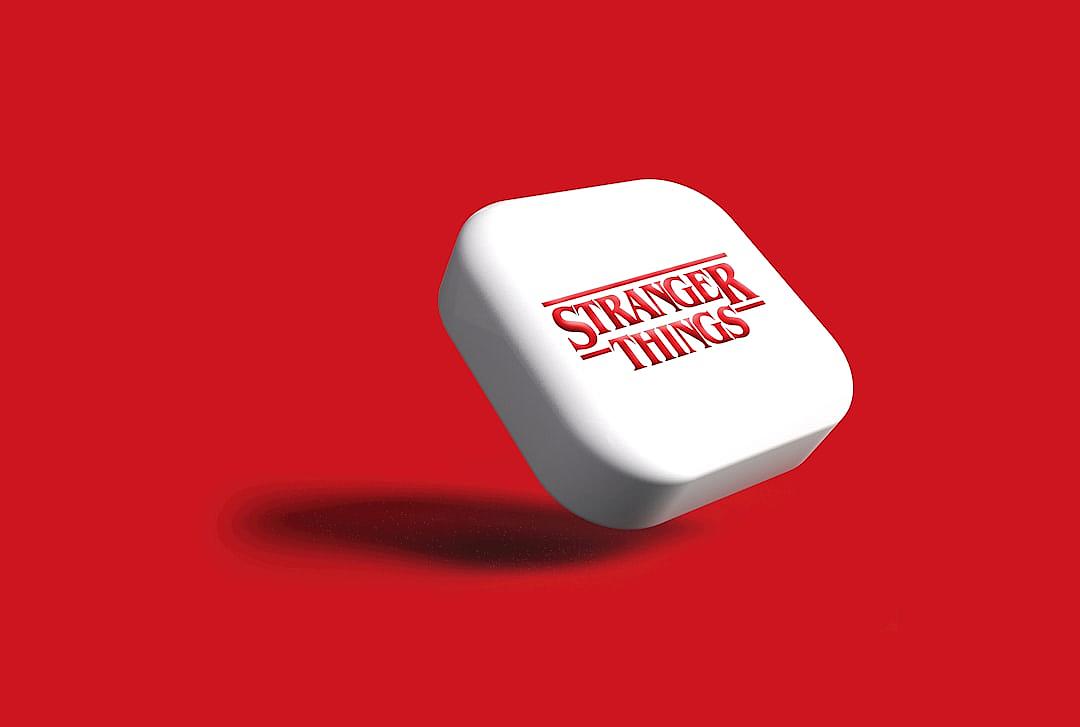 A white “stranger things” logo on the front of a small square cube with rounded corners, floating in air against a red background, isometric view, clean and simple design style, minimalism. The logo is displayed in the style of minimalism.