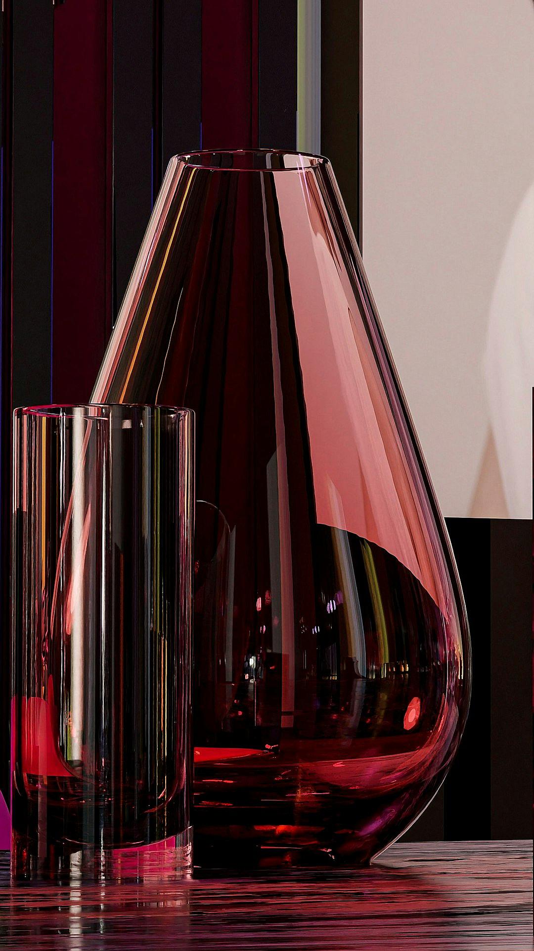 A large, dark red glass vase with sharp edges and a slender shape is placed on the table next to two transparent glasses filled with water. The background features a gradient of purple to black color that creates an atmosphere of luxury and elegance. In front of it stands another tall cylinder-shaped pink perfume bottle, adding depth to the composition. This scene embodies minimalism in design, showcasing a modern aesthetic with a touch of sophistication in the style of modern artists.