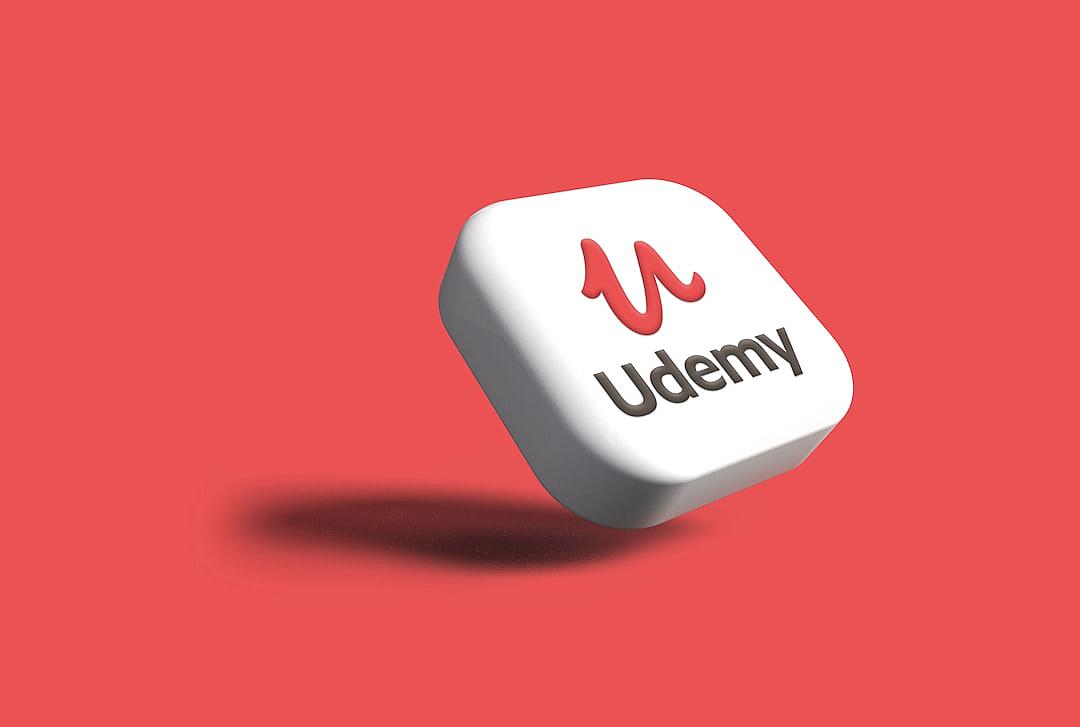 A white “Udormy” icon with red text floating on a solid color background, a 3D rendered logo design in the minimalist and simple shape style with high resolution. The logo is for the Udormy online school, featuring white and red colors in a simple shape made of simple lines resembling a white cube.