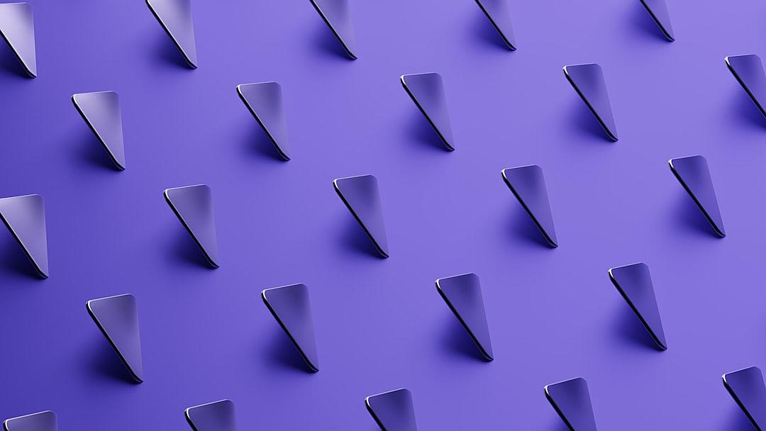 A series of identical triangular shapes are arranged in an orderly pattern on a solid purple background. The shapes have sharp edges and appear to be made from metal or plastic with a glossy finish. They form the shape of three triangles pointing upwards, creating an illusion that they go beyond the edge of the screen. This design is reminiscent of modern graphic elements found in digital marketing materials, in the style of minimalist graphic design.