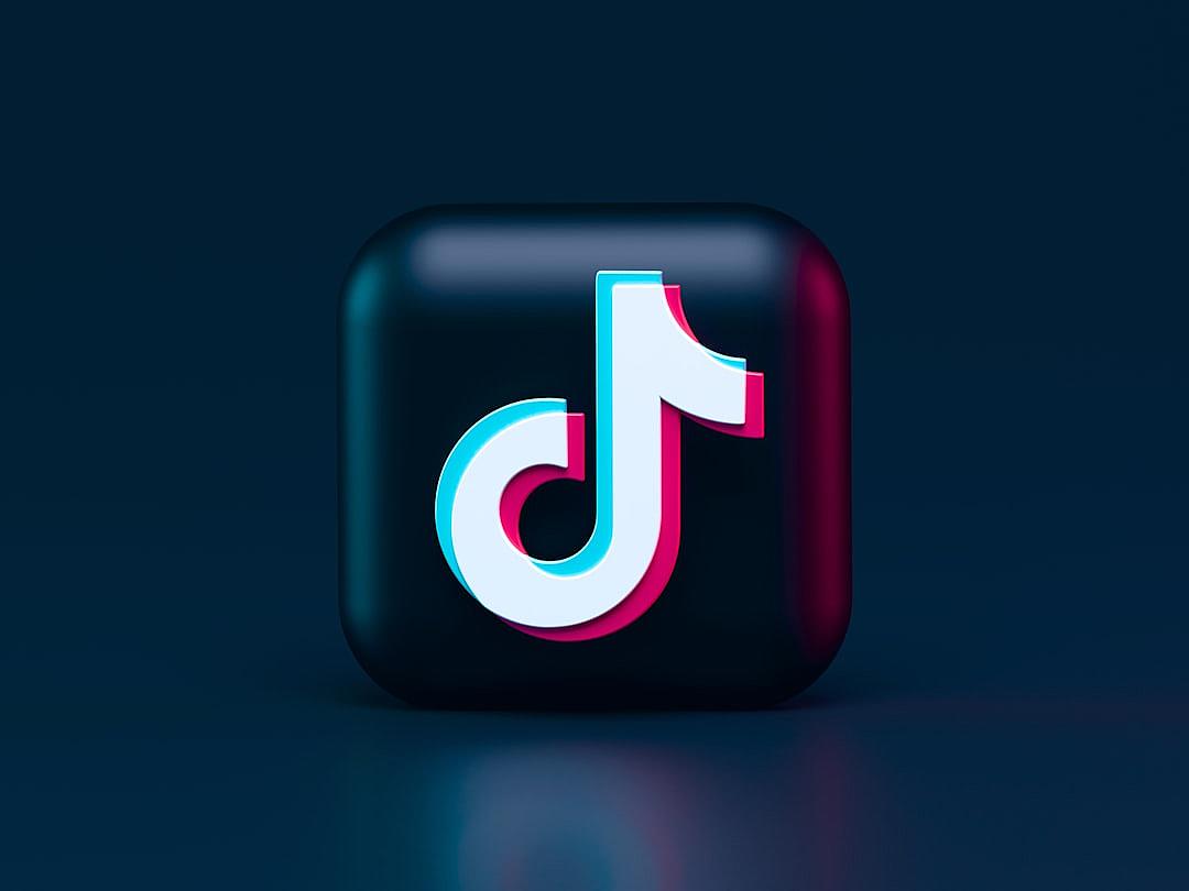 A modern logo for TikTok app, with the iconic white and pink “D” symbol on dark blue background. The icon is designed in 3d rendering style, with soft shadows cast by its edges. It has a glossy finish that reflects light beautifully, creating an eyecatching effect. This design adds depth to your social media profile page, making it stand out among other logos.