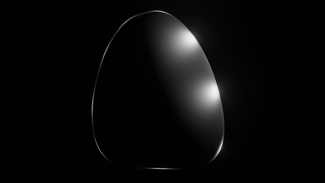 A black background with an oval shape in the center, resembling an egg. The oval is dark and smooth, with soft lighting that casts gentle shadows on its surface. It has a glossy finish and appears to be made of metal or glass. There’s no text visible but it seems like there could have been some design elements on top of the oval shape. This graphic illustration captures simplicity while conveying elegance through its clean lines and minimalist style.