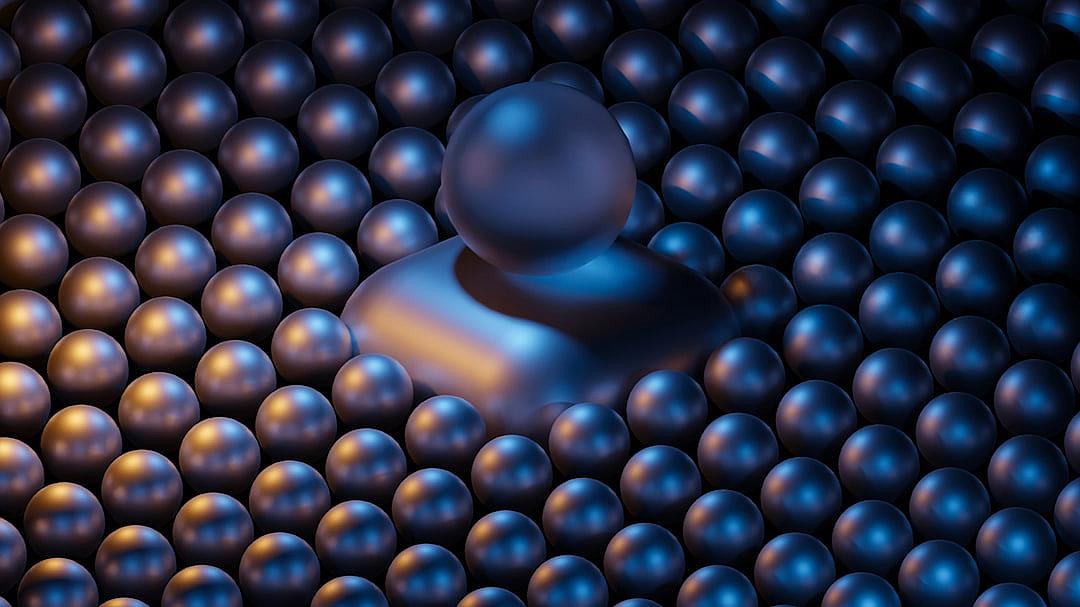 A person surrounded by an array of metallic spheres, creating the illusion that they have opened up to reveal their inner world and personality. The background is dark blue with soft lighting.