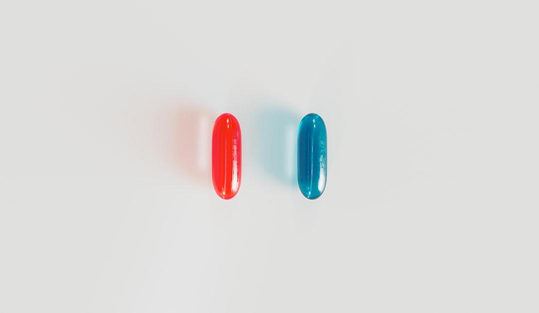 Two pills on a white background, one red and the other blue, in a flat lay photography style, with a minimal concept, and studio lighting, photographed in the style of an art director.