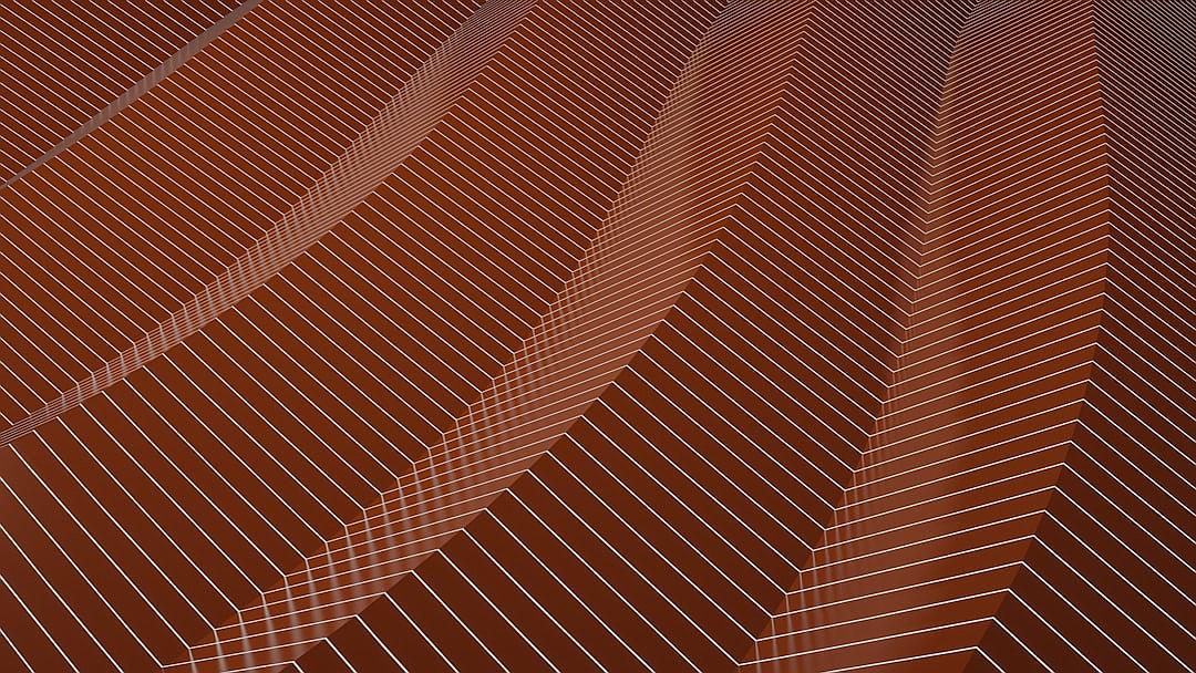 A closeup of the terracotta wall, with thin white lines drawn on it in an angular pattern that forms herringbone shapes. The background is solid brown and the foreground focus color is dark red. There’s no other detail or text visible. This design creates a modern aesthetic, with the patterns adding depth to the wall surface.