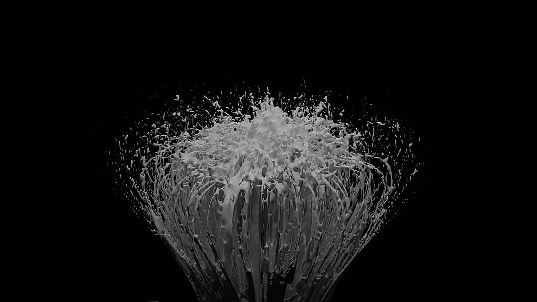 A monochromatic water explosion on black background, dynamic and powerful, with a splash of white against the dark backdrop. Highcontrast lighting captures every droplet in motion, creating an intense visual effect. The splashes form intricate patterns that add depth to the scene. A subtle gradient from light grey at top gently transitions into deep shadows below. This visual representation is designed for highdefinition video rendering, showcasing each drop’s impact in stunning detail.