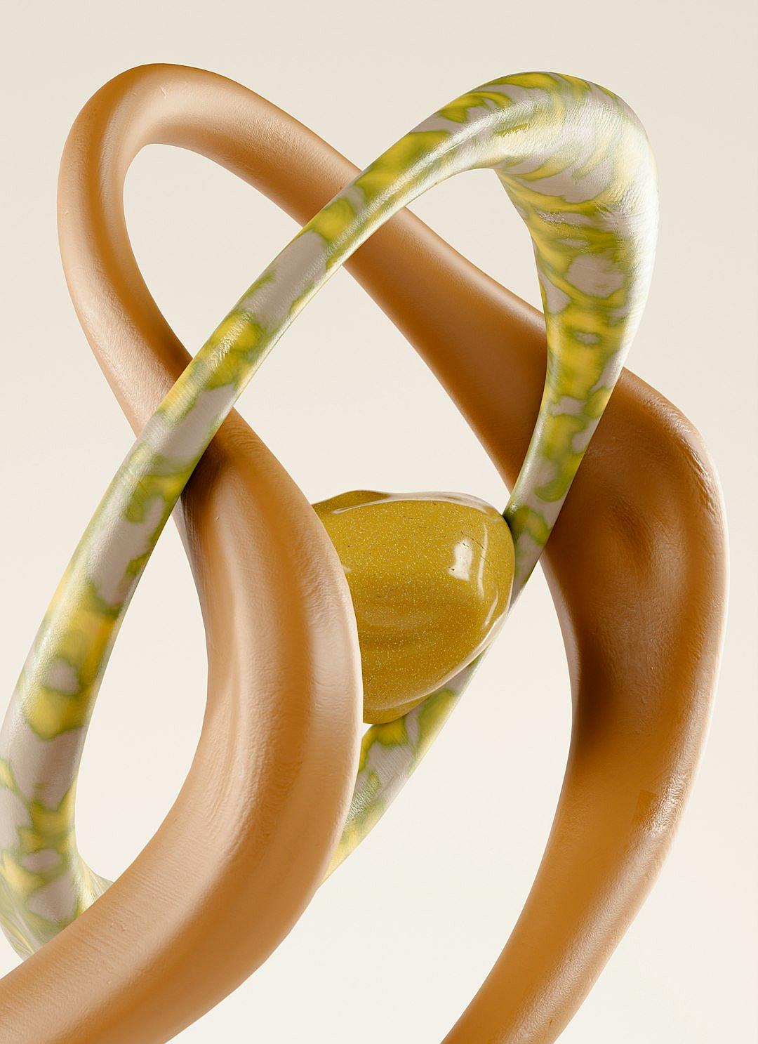 A closeup of an abstract sculpture with two intertwined rings, one in light brown and the other in pale yellow. The rings have a smooth texture that reflects a soft glow from within. They appear to be made out of rubber or plastic material, giving them a slightly wet appearance. There is also some greenishblue patterns on their surface, which adds depth and contrast against the white background. In its center lies a small circular piece, possibly painted gold.