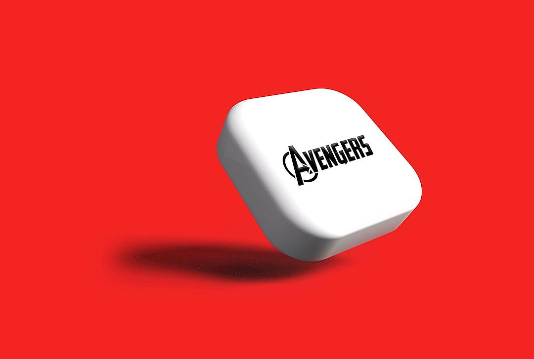 A white rounded square shaped device with “avengers” logo on it floating in the air against a solid red background. The design style is clean and simple with a minimalist aesthetic. It appears to be product photography with studio lighting and high resolution.