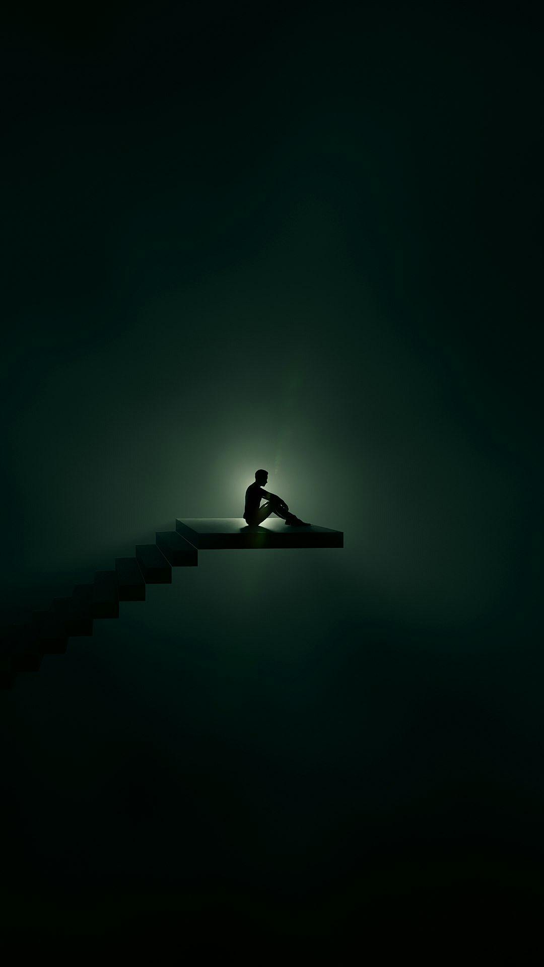 A man sits on the edge of an endless staircase against a dark green background in the style of minimalism photography. The silhouette lighting and backlighting create a low saturation and sense of loneliness and despair. Black space appears above his head with no light in front of him, only faintly shining from behind.