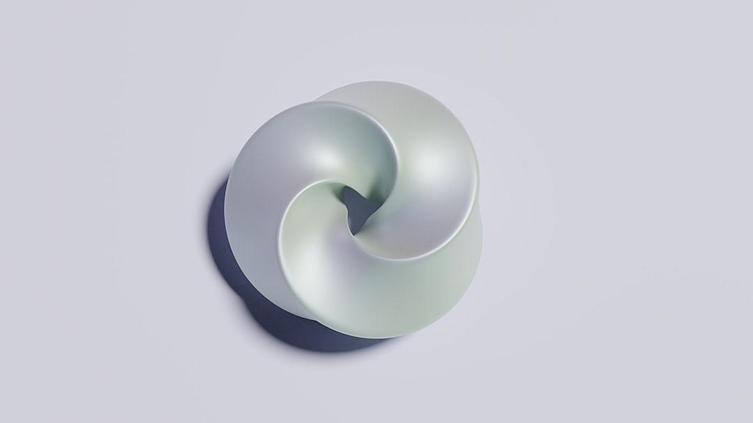 A simple, soft and rounded shape with a pale green color on the top is placed in an empty space, with a gray background. The design of C4D has been created using Cinema 3d. It’s made from clay material, featuring studio lighting, highquality images, and a minimalist style. This shape forms a spiral pattern that adds visual interest to its appearance. It also creates depth through its use of shadows.