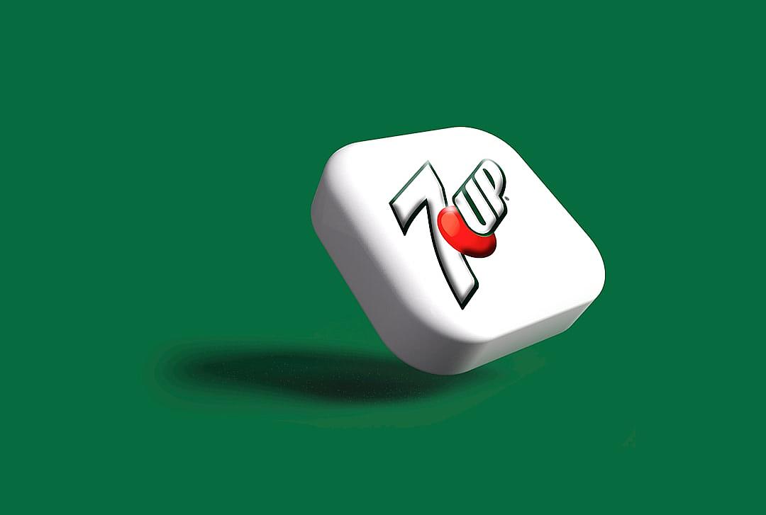 A white cube with the “7 Up” logo on it, floating in midair against a green background. The cubes have rounded edges and feature red highlights around their center point. There is no shadow cast by them, indicating they may be used for graphic design or branding purposes. This scene could represent an icon or symbol associated to whquareshaped drink from different angles, 3d render, cartoon style