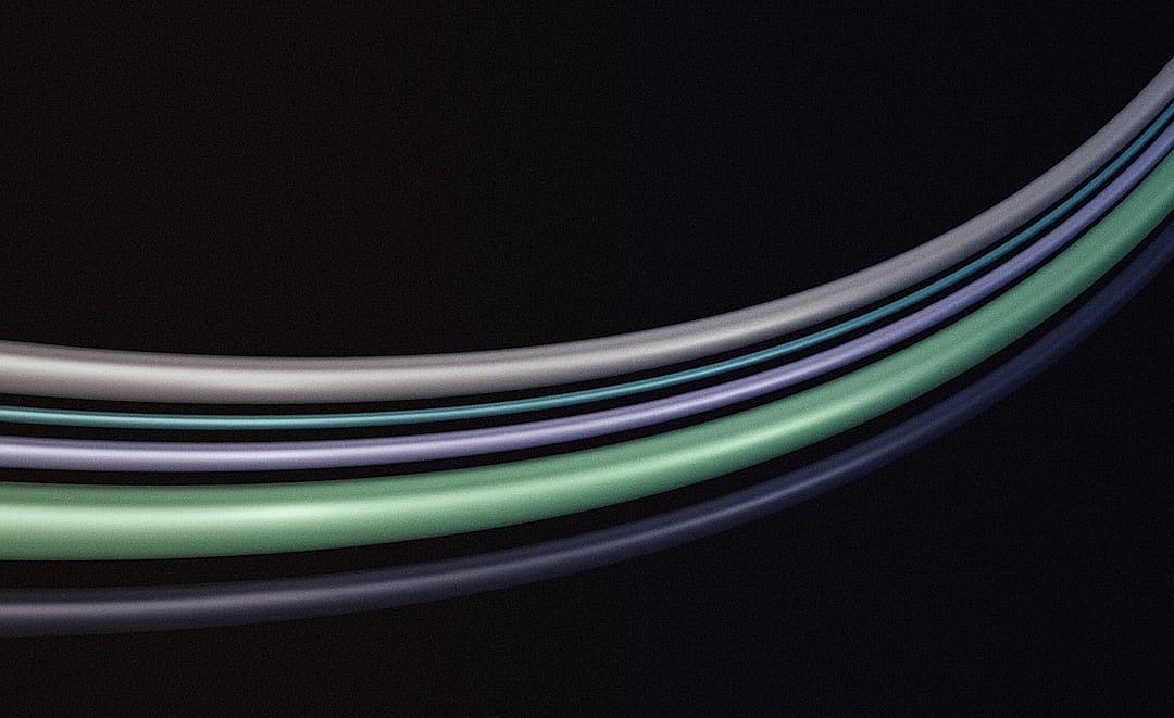 A closeup of four curved, smooth wires in different colors and sizes, each set against a dark background, creating an abstract composition with soft lighting that accentuates the curves and shades of green, blue grey and purple, conveying depth and contrast between the wires and their surroundings.