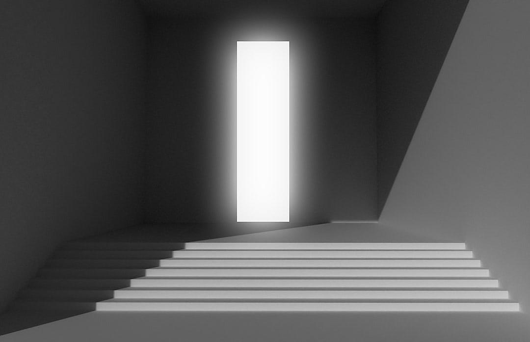 White stairs lead up to an open door with light shining through, on a black and white minimalist background, with high contrast, clean lines, and perfect symmetry, in a high resolution, photorealistic, hyperrealistic style resembling the interior design photography and art installations of [James Turrell](https://goo.gl/search?artist%20James%20Turrell).