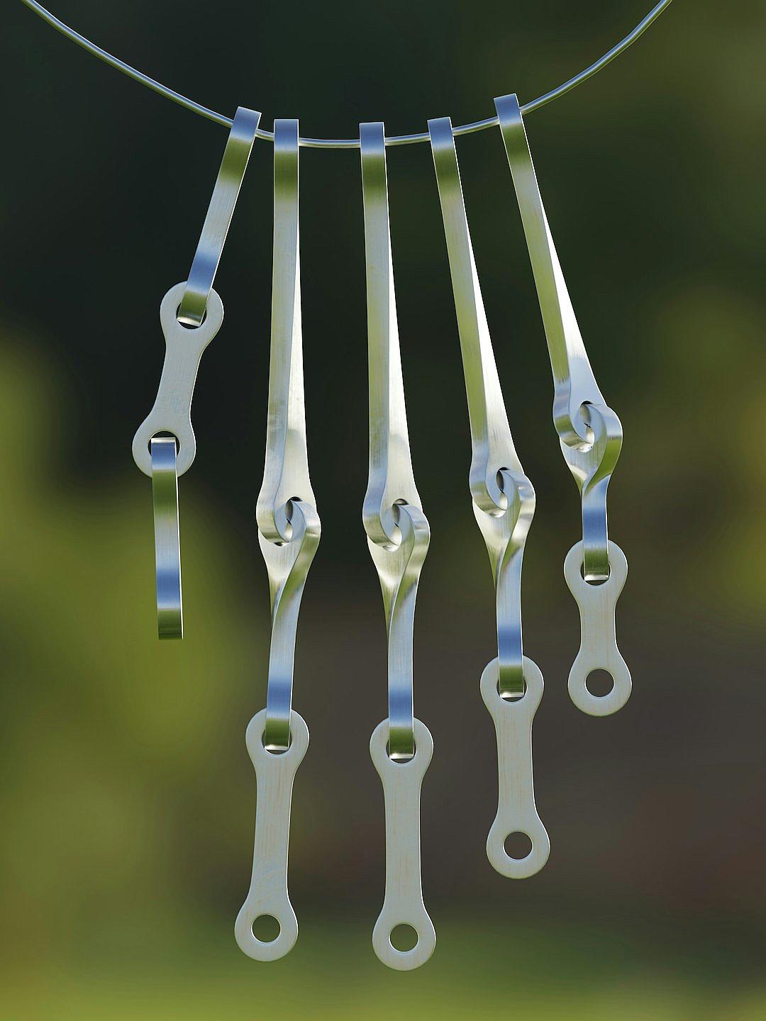 A photograph of five stainless steel cutlery pieces hanging on a wire, with a green background. The cutlery have different shapes and sizes. They appear to be suspended in midair by wires that can only be seen from above. Each piece is made up of straight lines and curves, giving it an elegant appearance. This photo was taken using a Canon EOS camera with a macro lens in the style of minimalist photography.