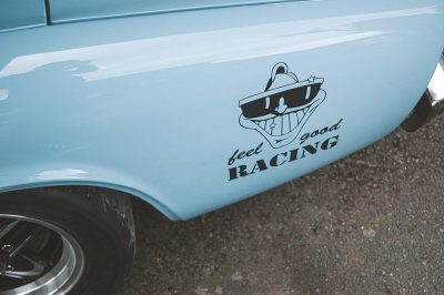 sticker on the side of an old light blue muscle car with cartoon style text " fe details racing feel good