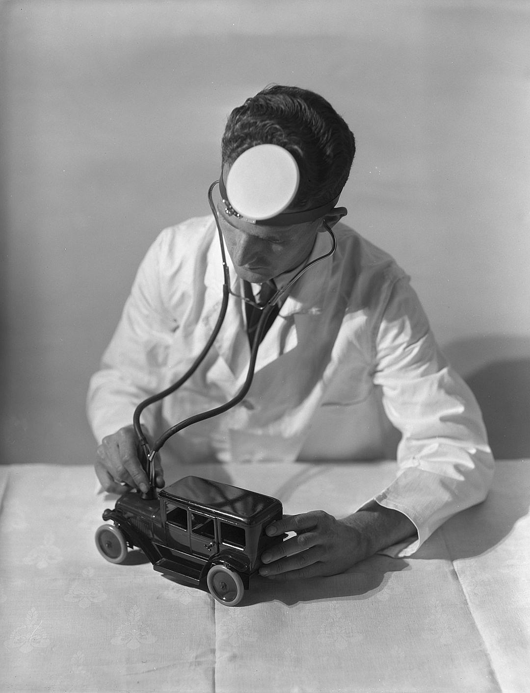 A doctor in a white coat using his stethoscope to check the sound of an old toy car, photo in the style of kodak camera.