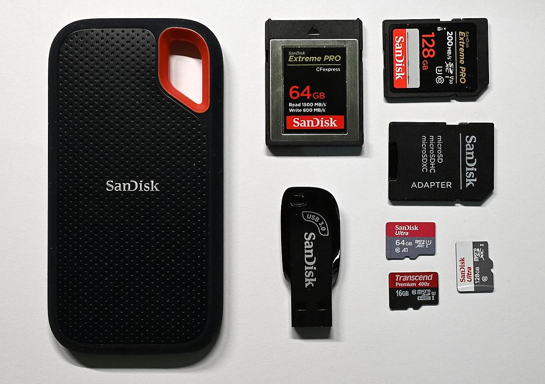 A photo depicting the “SanWithEmailAndPassword” card with an open flash drive, next to it are two black and red micro Obcettes Pro Max cards, one white San Shotgun 64250g ZIU button stands on top of them. The background color should be pure white. There must also be several sandisk thLewispro cards partly visible and some San FilmsD prose soft 39 “, one slight 79”, and another slightly larger san. Maria figures engaged in crying and speaking to each other, with expressions of deep sadness and pain. They all wear similar  and appear in the style of Anthropomorphic.