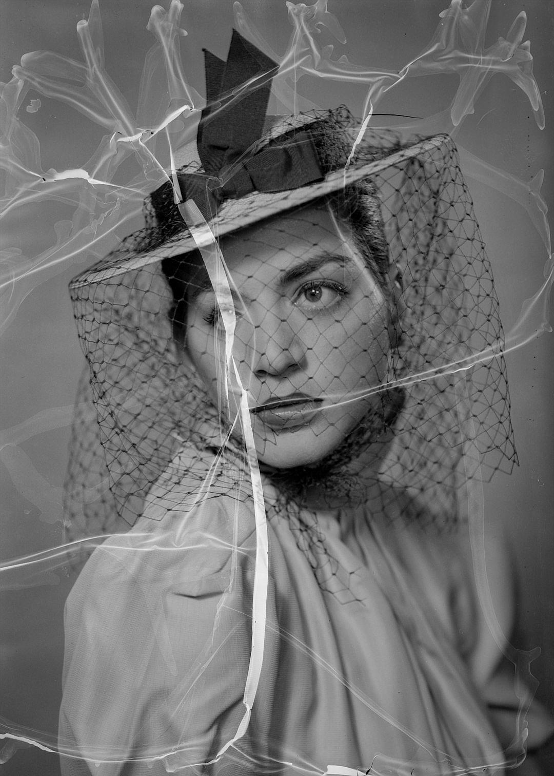 photonegative refractograph portrait of a woman in a vintage hat with a veil, haute couture fashion photography, magazine cover, 35mm film grain, high contrast, dynamic composition, soft focus, ethereal details, captured in the style of a Leica M6 camera and Portra Pro mist filter, surrealism, chiaroscuro lighting, dreamy atmosphere, vintage fashion style.