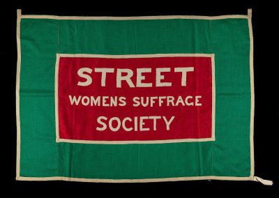 A green and red banner with the words "STBook street women's art Scene society" on it, with a white border around all sides of the flag.