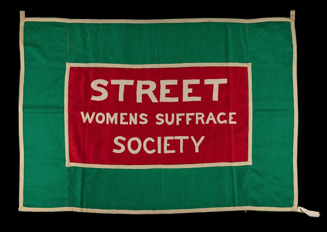 A green and red banner with the words “STBook street women’s art Scene society” on it, with a white border around all sides of the flag.